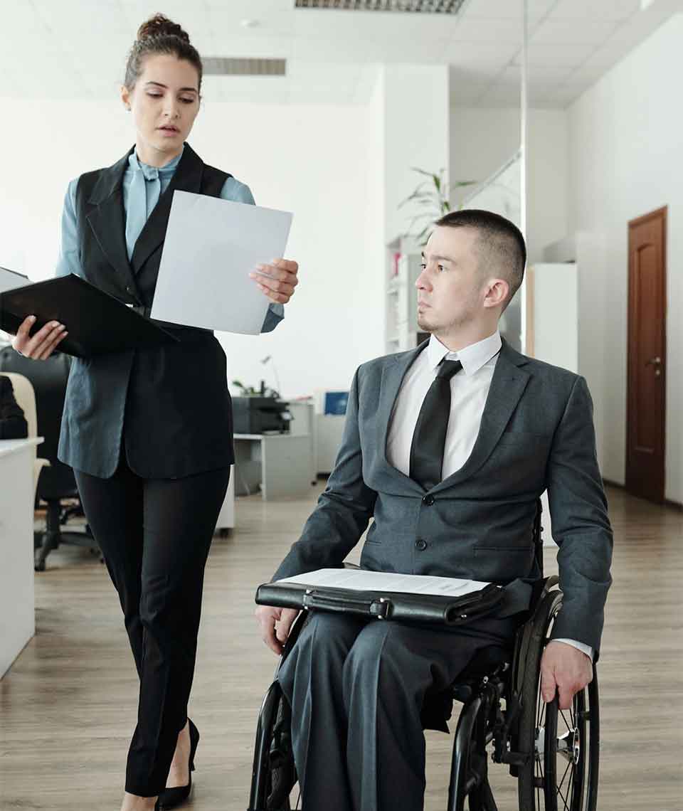 Special Needs Trust Attorney Denver Businesswoman reviewing documents with colleague in wheelchair - Special Needs Trust Attorney Denver